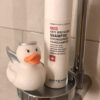 Dusche mit weissem Shampoo von Artemis Med und einer weissen Quitscheente mit Heiligenschein