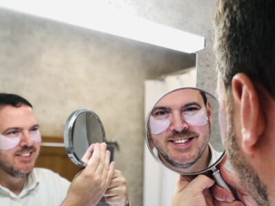 Mann mit Eyepads strahlt sich im Spiegel an