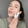 Junge Frau mit Lippenpflege in der Hand, mit Kussmundpose